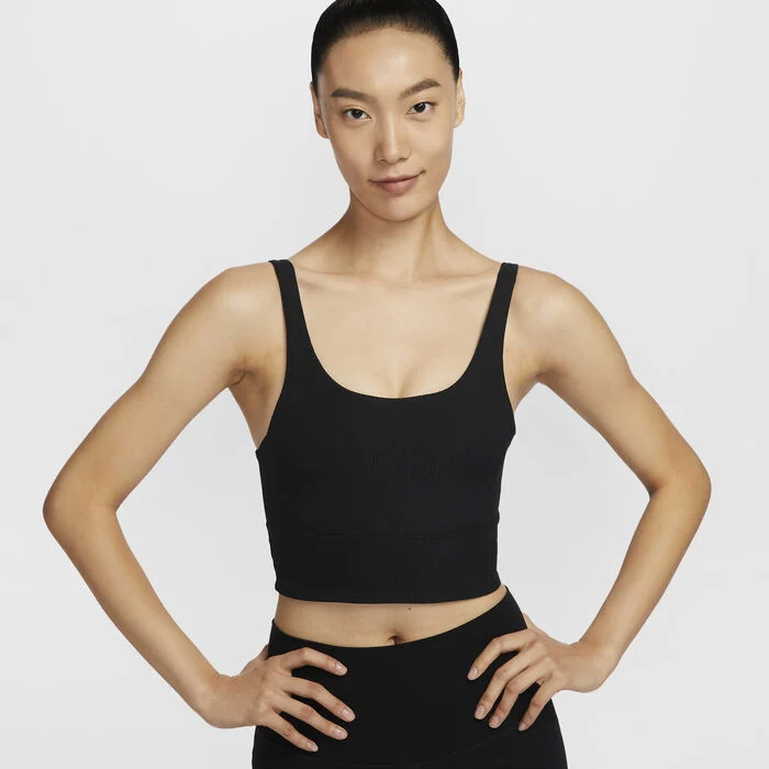 Woman wearing a black Nike cropped sports top with a supportive fit, suitable for yoga and low-impact training