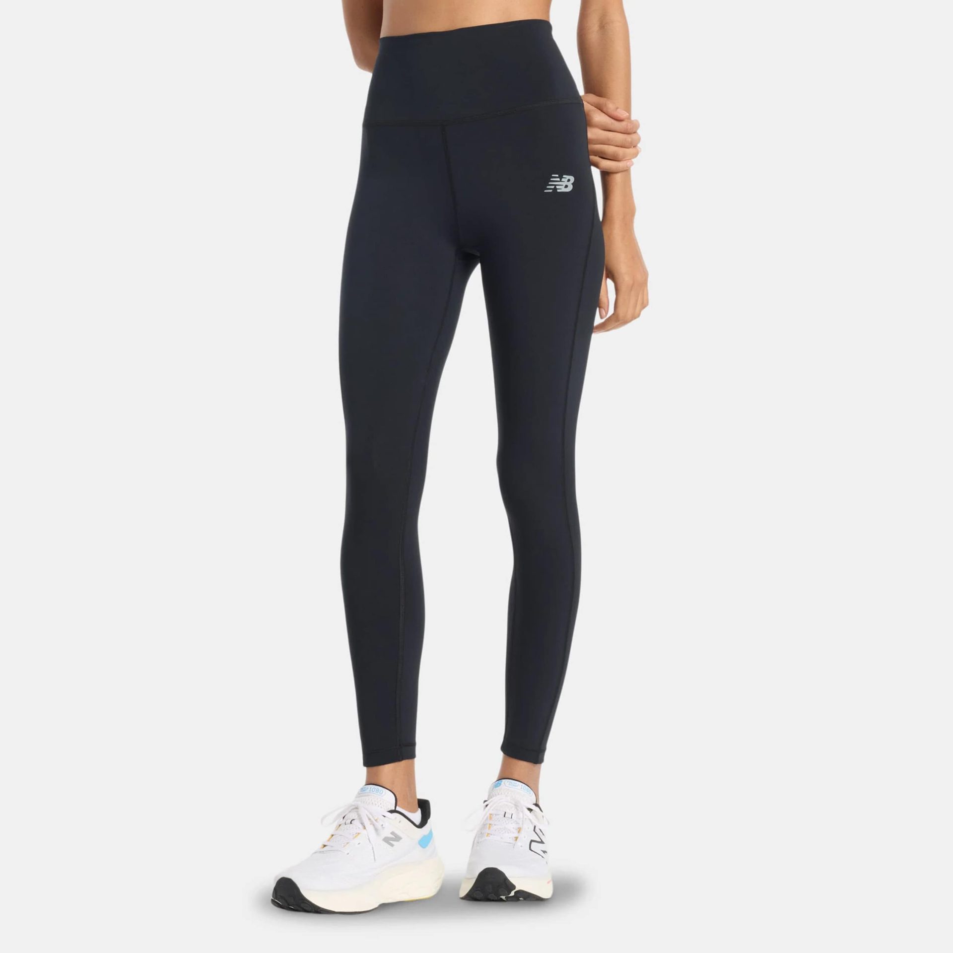 Woman wearing black New Balance high-rise sport training leggings paired with white running shoes