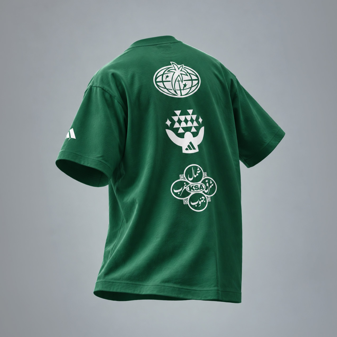 Back view of green Adidas men’s Saudi graphic t-shirt with white cultural emblem prints